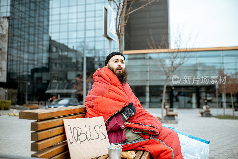 无家可归的乞丐坐在商业中心附近的长椅上