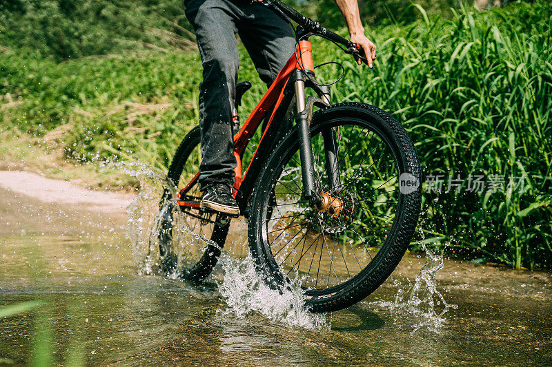 男人骑着自行车穿过水坑