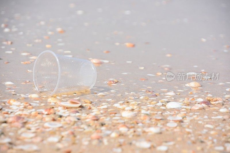 塑料污染，杯子遗弃在沙地上