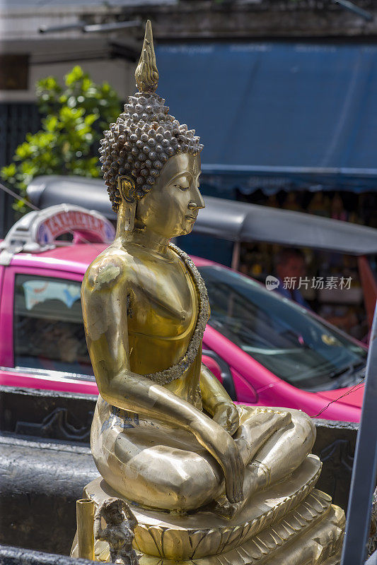 泰国佛像坐在一辆皮卡车的后面，在曼谷的交通堵塞中，正在被送往某个地点的路上。