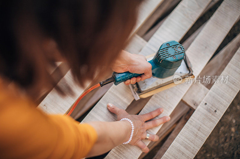 忙碌的DIY妇女在建筑工地上刮木板