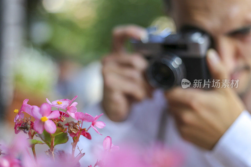 半长青年美男子在城市户外手持速成相机，拍摄-摄影，创意，艺术理念。模糊的观点，时尚的男人拍照在复古的相机。