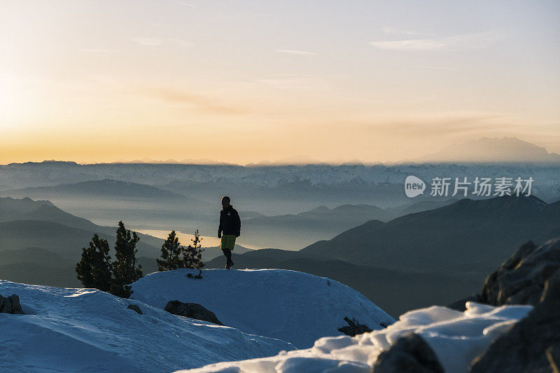 黎明时分，一名徒步运动员爬上雪山的山脊