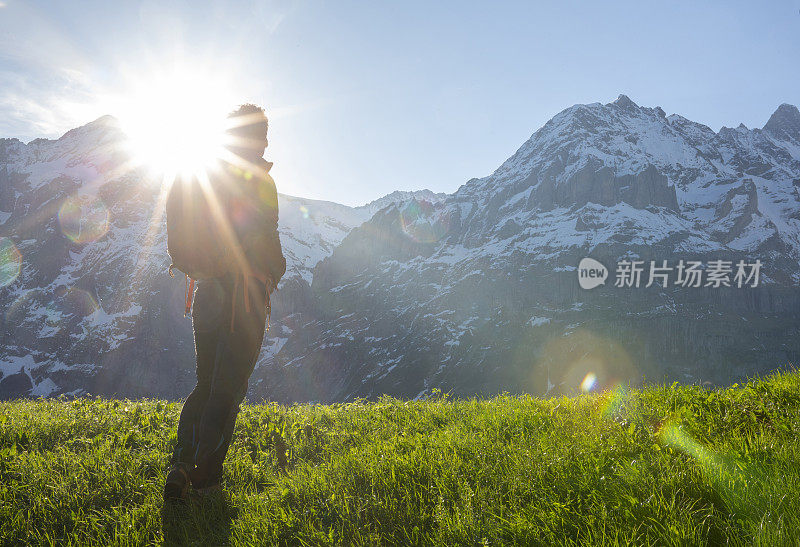 男性徒步者攀登山上的草甸斜坡