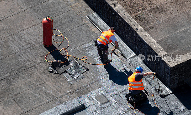 屋顶建筑工地的鸟瞰图。专业沥青防水在平坦的建筑上。