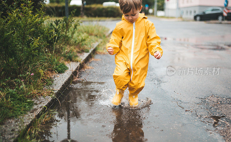 小男孩在雨中玩耍，跳进水里画画