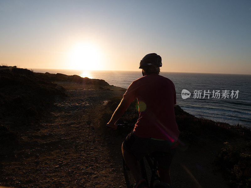 日落时分，山地车手在悬崖边骑行