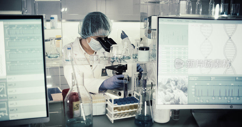 研究DNA突变的女医生。在防护服中使用显微镜