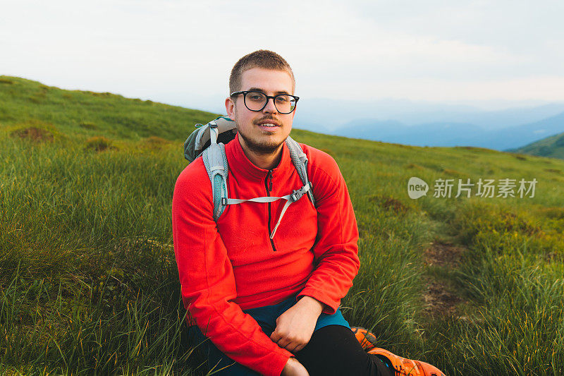 年轻的背包客在草地上放松，在山上欣赏日落