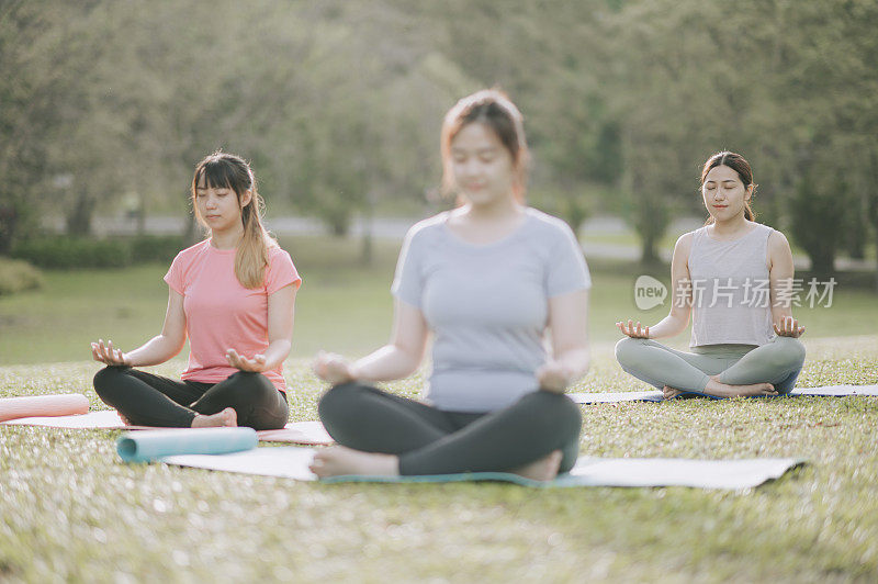 3个亚洲中国年轻女性在周末的早上在公园练习瑜伽