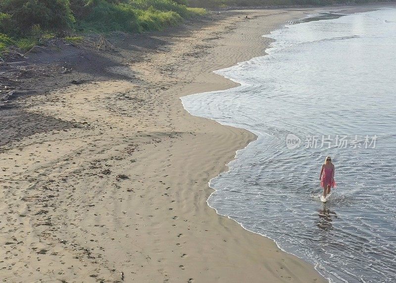 鸟瞰图的女人走下沙滩在日出