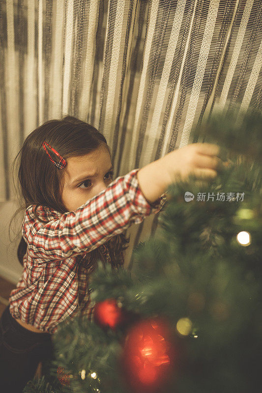 小女孩装饰圣诞树的选择性焦点
