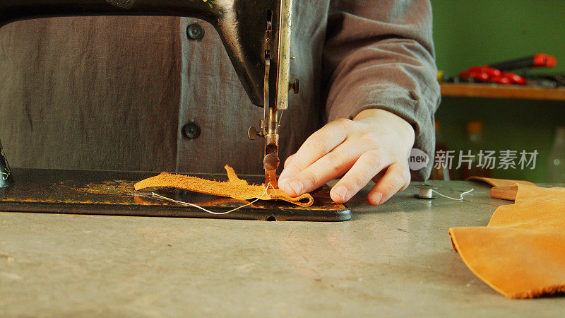 一名裁缝在车间里用缝纫机做了一个用真皮革制成的独一无二的包