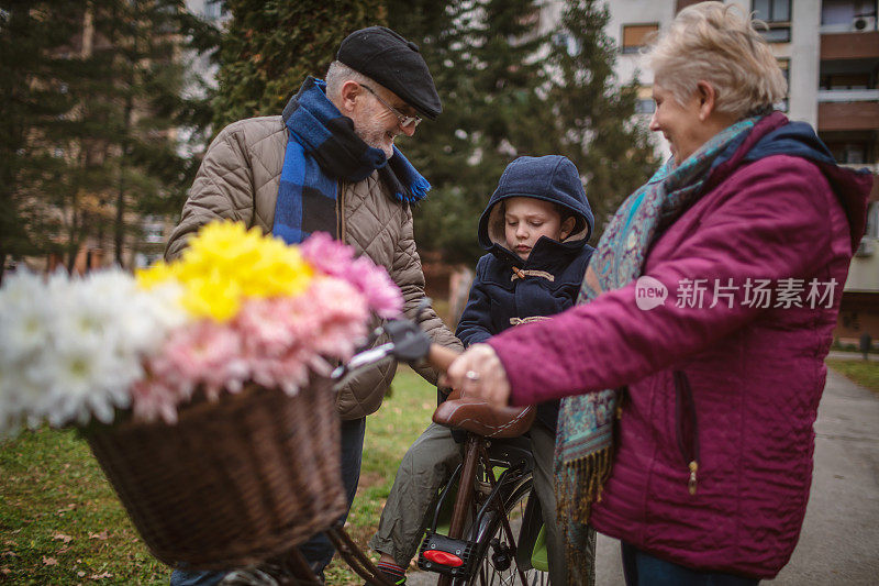 活跃的老夫妇和孙子在户外骑自行车散步。