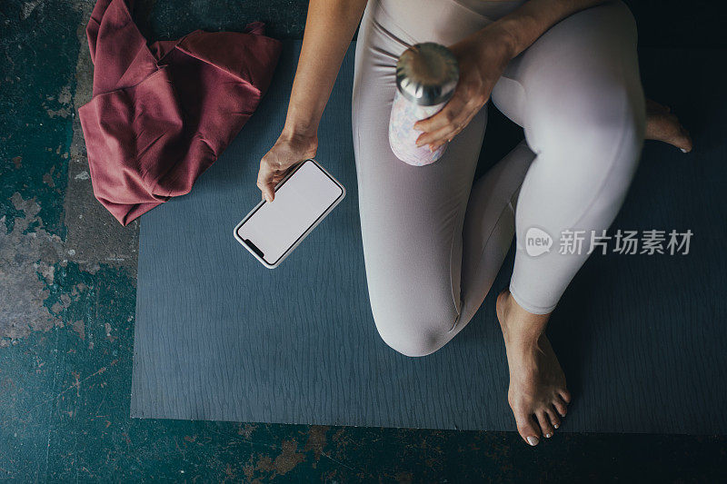 在家里用智能手机做瑜伽的陌生金发女人(黑屏，复制空间)