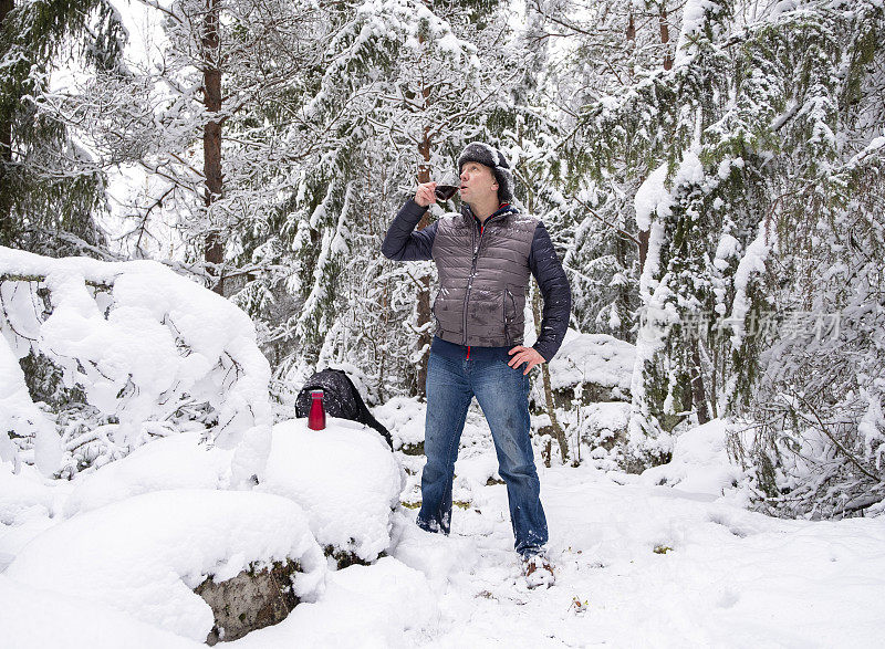 白种人在冬天的雪地里。那个人正在休息和喝咖啡。步行旅游。