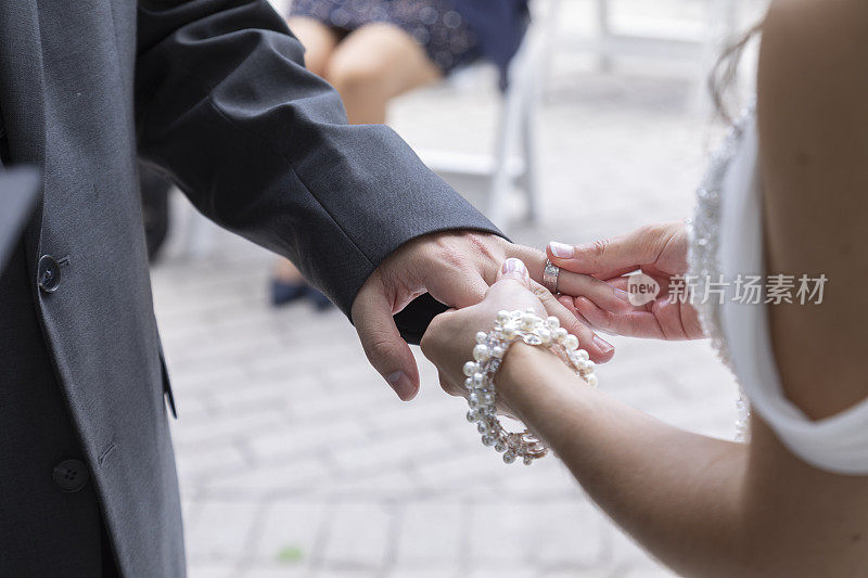 在户外举行的婚礼上，新娘给新娘戴上戒指