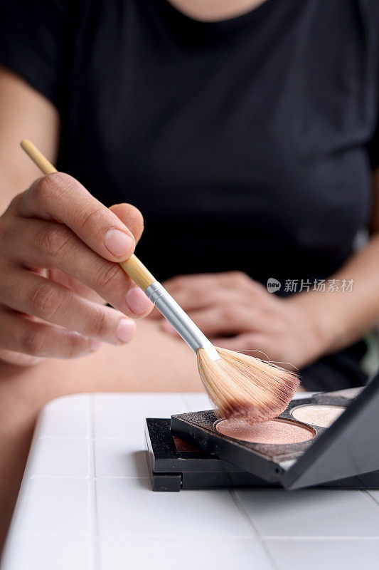 女人手里拿着化妆刷蘸着粉