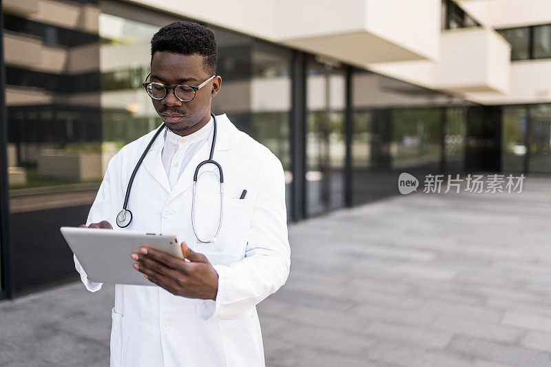 年轻男医生在医院门前使用数码平板电脑。