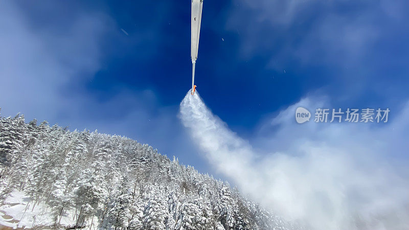 雪炮在滑雪坡和树木上喷洒人工雪