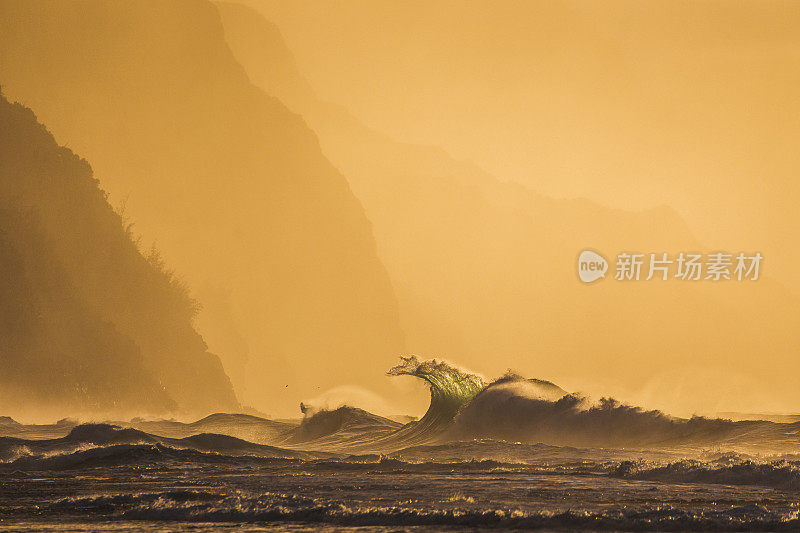 汹涌的海浪在午后温暖的金色阳光下破碎，背景是高耸的海景山