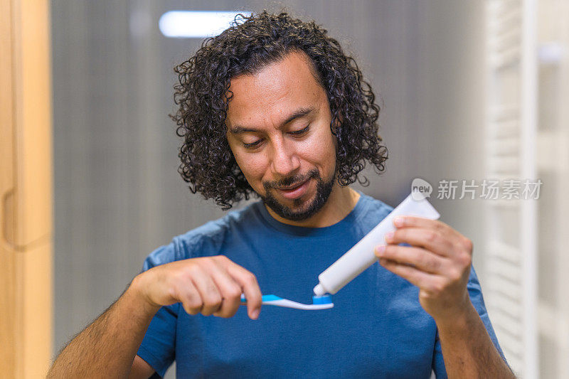 近距离观察西班牙裔男子在牙刷上涂牙膏