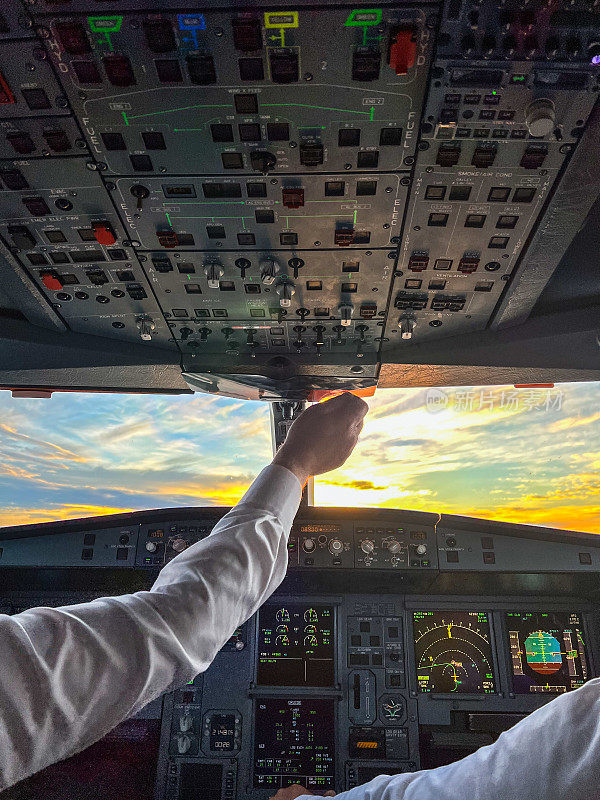 驾驶舱设备飞行员手按按钮垂直拍摄日出时的飞机部件