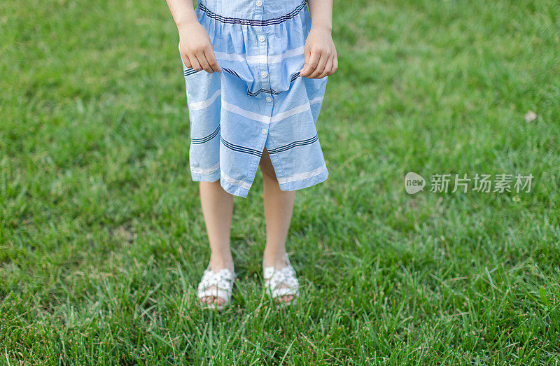 小女孩穿着凉鞋站在草地上