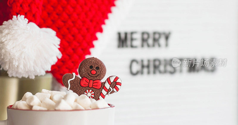 一个写着“圣诞快乐”的牌子，圣诞老人帽子，一杯热可可，棉花糖和姜饼人，背景是一个美丽的bokeh。温馨的新年和寒假概念。