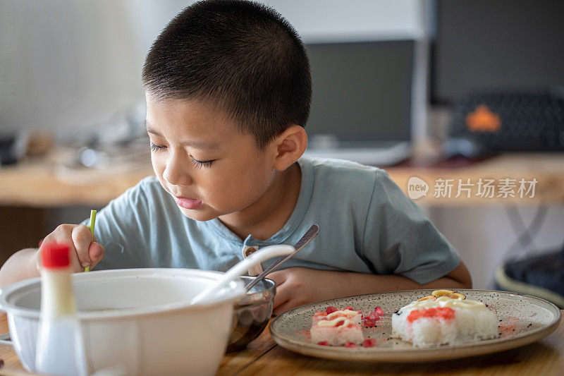 一个小男孩独自坐在桌旁吃饭