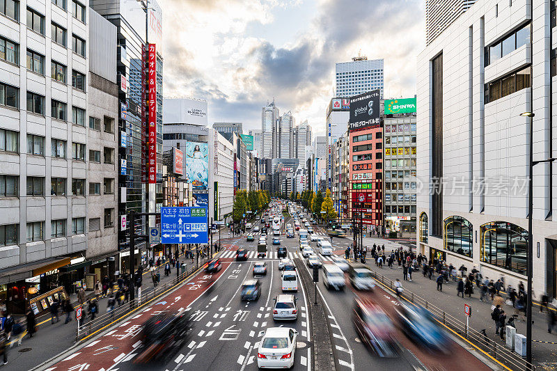 运动模糊的汽车交通运输在十字路口，日本人走在日本东京新宿区十字路口，办公大楼的城市景观。亚洲交通，亚洲城市生活理念