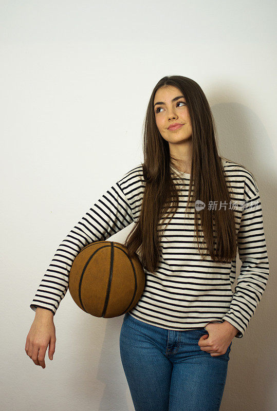 一名年轻女子拿着篮球摆姿势的摄影棚照片