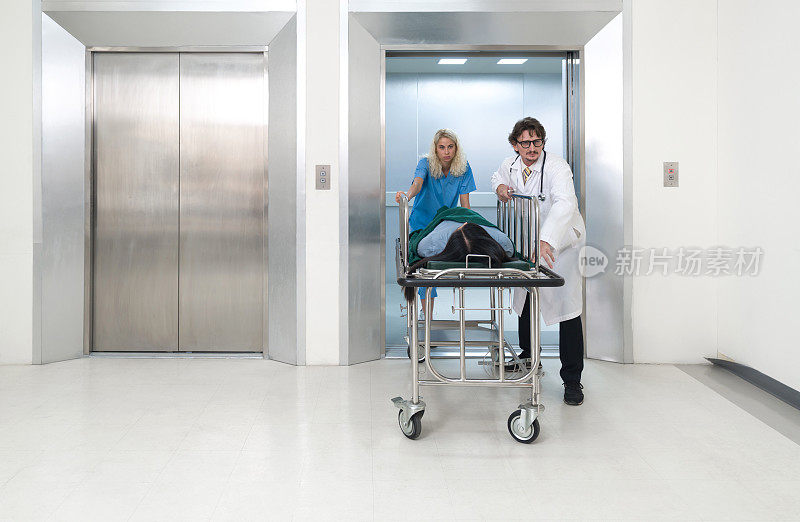 护理人员和护士把病人的床从电梯里推到医院的急诊室。
