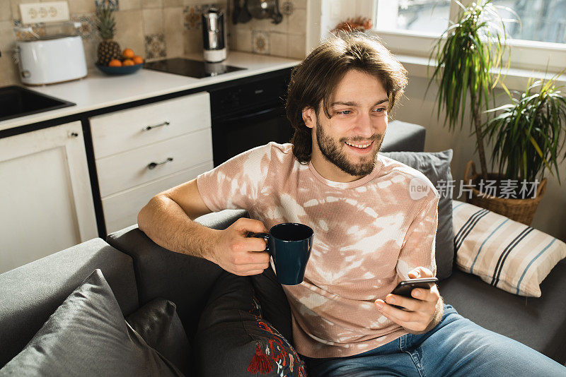 图为一个年轻人一边喝咖啡一边用智能手机打视频电话