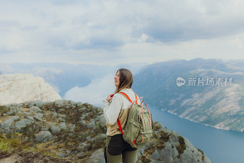 快乐的女背包客在挪威欣赏田园诗般的吕瑟峡湾