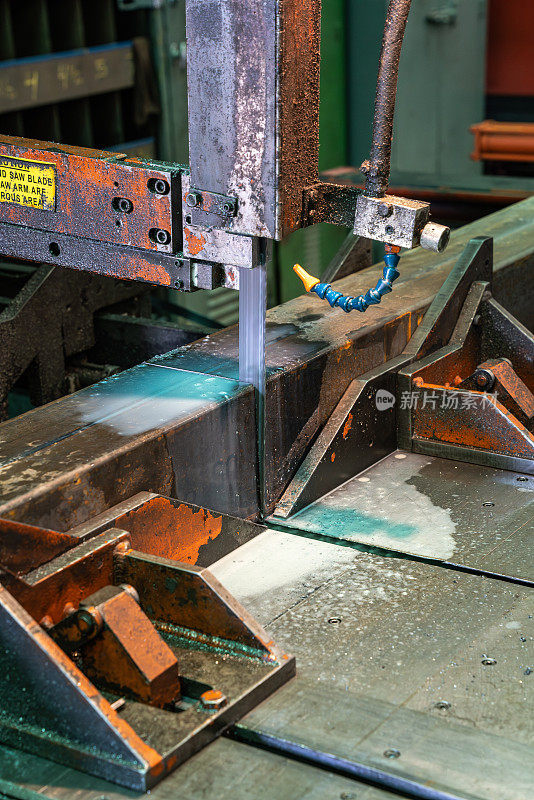 一个钢铁加工车间的戏剧性图像，机器切割方管钢。