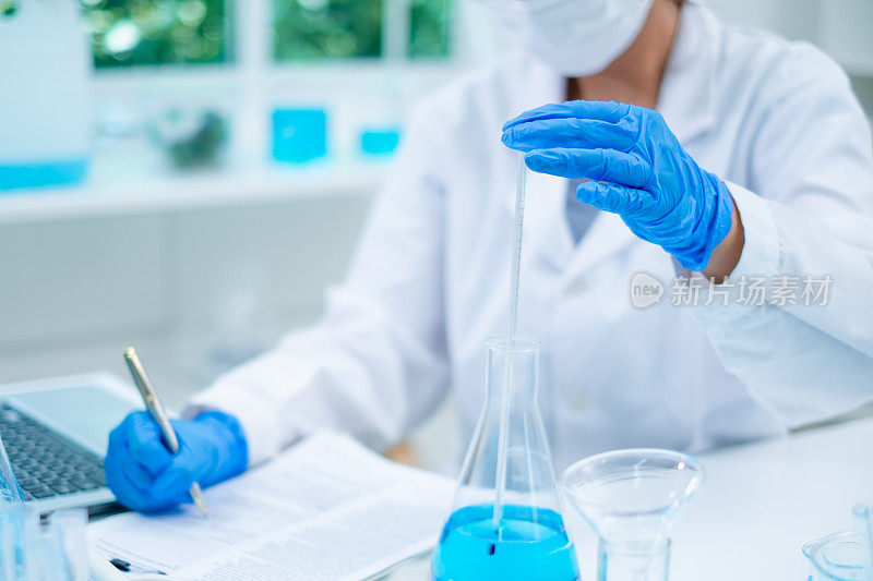 一位女科学家正在实验室里测量物质的温度。检验生物技术和医学研究、检验、检验或发现样品液质量的概念。