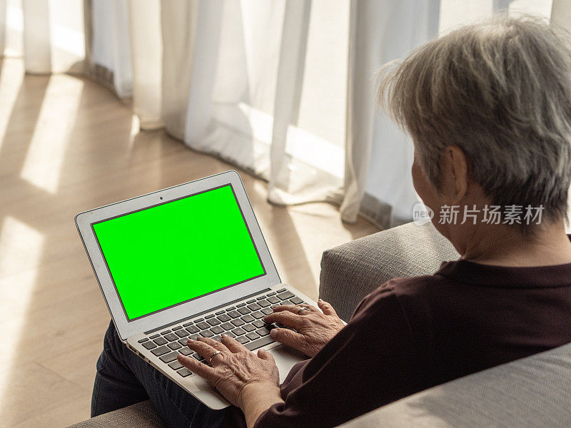 人物-一位亚洲华裔老年妇女在生活区使用笔记本电脑的画像(绿屏)