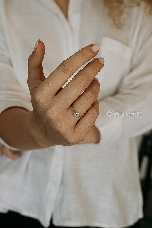 年轻女子的手上戴着一枚钻石戒指。新娘的结婚饰物。