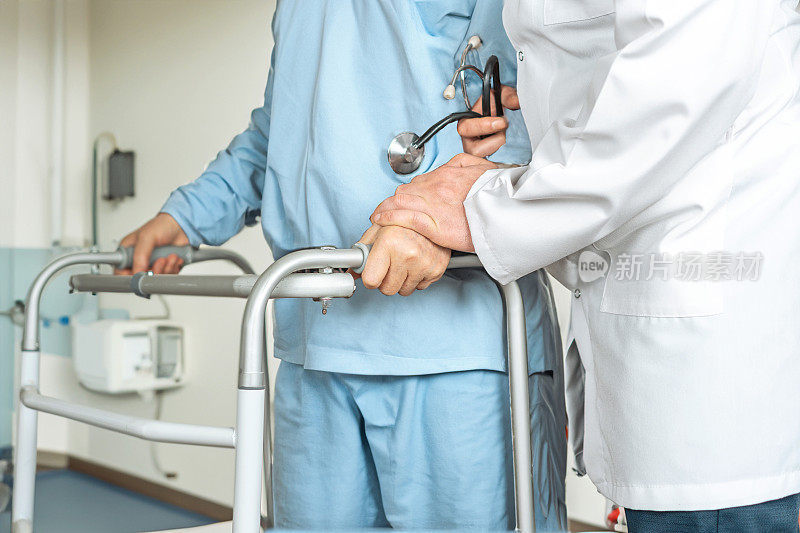 医生在医院病房帮助老年妇女病人用助行器行走