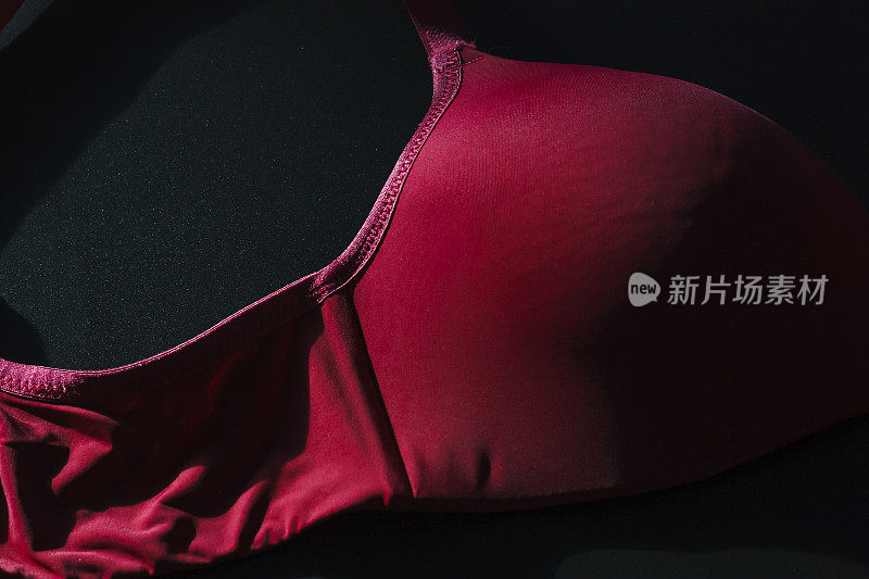 近景拍摄的现代经典性感的红色无缝平滑的无衬里的女性胸罩在黑色的背景。