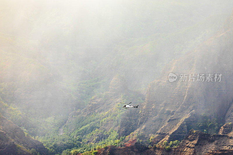 直升机在夏威夷雄伟的山脉和山谷的雨和雾中飞行