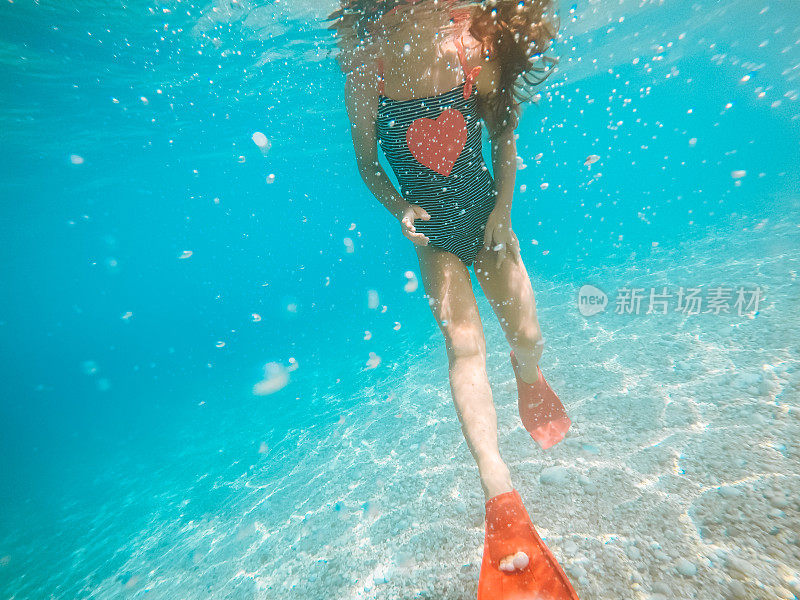 穿着红色脚蹼的女孩在她的暑假里在水下游泳