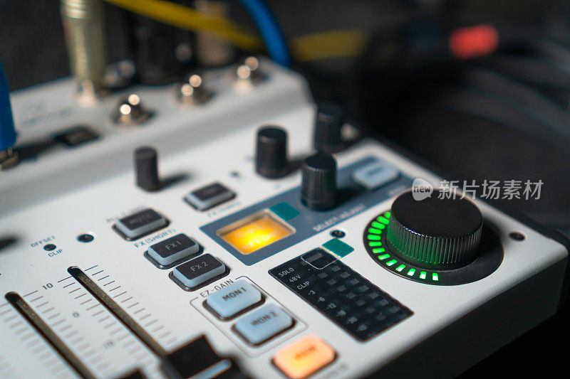 近距离图像的手调节混音旋钮的音量控制在现场演播室的表现。Mixer具有多个旋钮和按钮，用于精确的音频混合调整。
