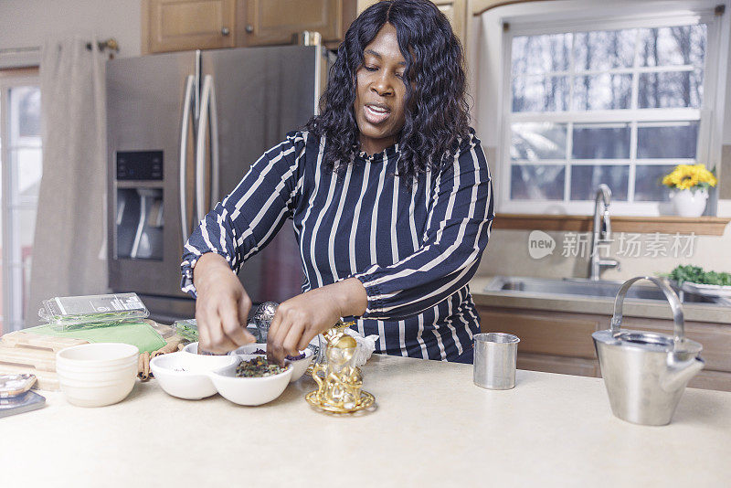 在她的厨房里，一位成熟迷人的非裔美国黑人妇女正在煮花草茶。