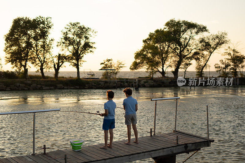 小男孩在日落时在湖上钓鱼。钓鱼的爱好