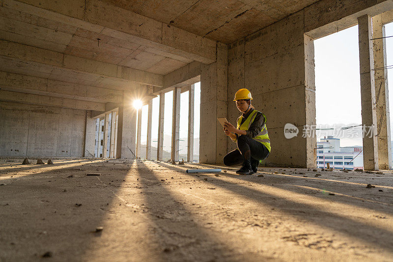 一位亚洲女建筑工人正在工地上使用平板电脑