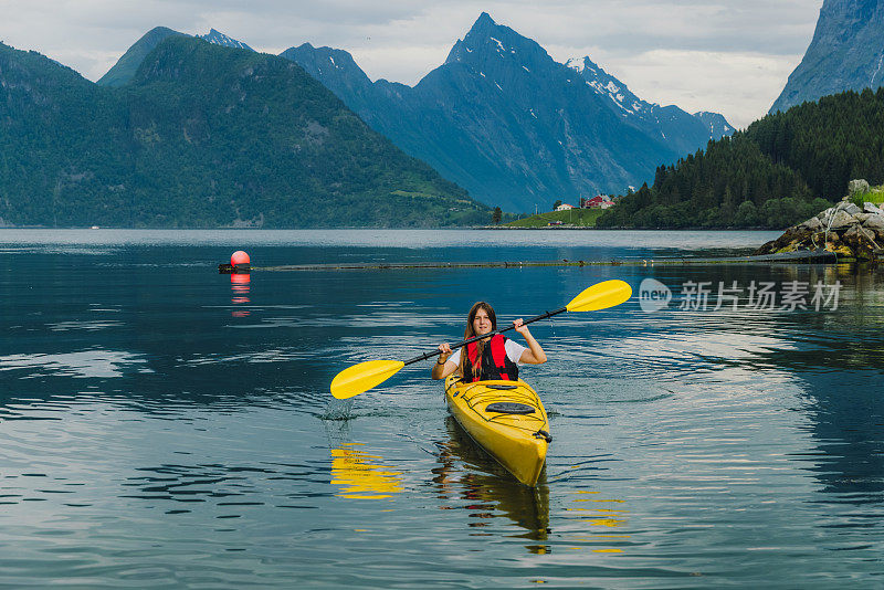 在挪威风景优美的峡湾上划着皮艇的女游客