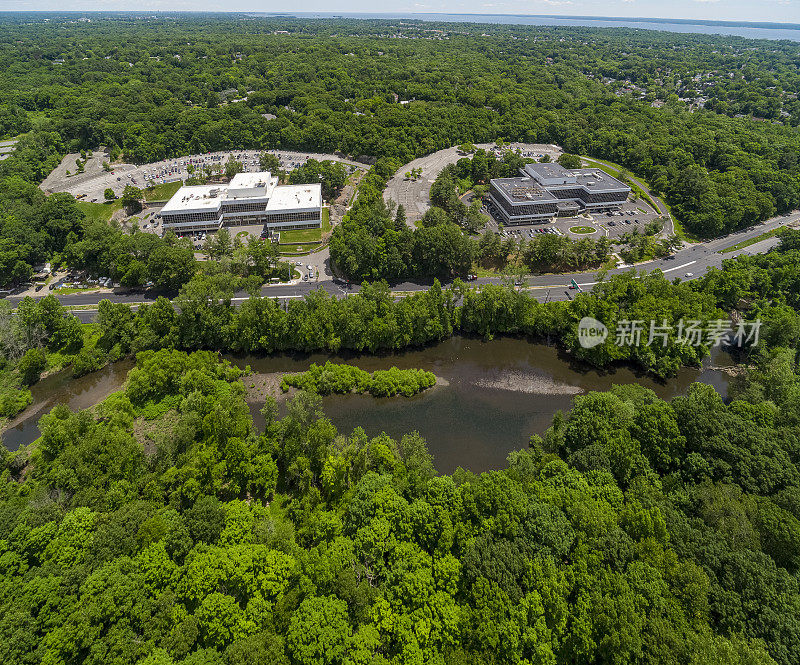 一个阳光明媚的夏日，位于郊区社区的购物和办公中心。空中缝合全景。