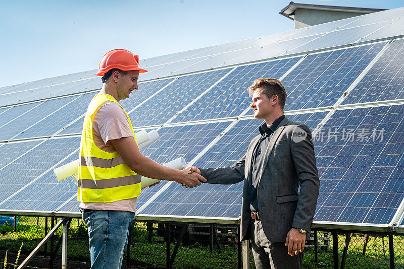 在可再生能源协议达成后，对着太阳能板握手